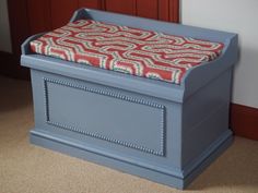 a blue bench with a red and white blanket on it's seat cover sitting in front of a door