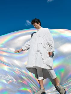 a man in white shirt and shorts standing on a holographic object with his hands out