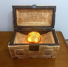 an open wooden box sitting on top of a table next to a light in it