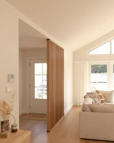 a living room filled with furniture and windows next to a wooden floor covered in white curtains