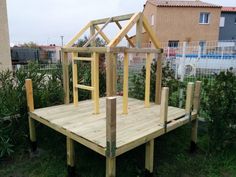 a house made out of wood sitting on top of a wooden platform in the grass