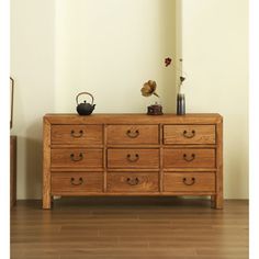 a wooden dresser sitting on top of a hard wood floor next to a white wall