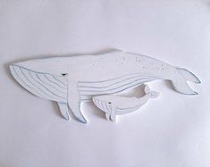 a ceramic whale is hanging on the wall in front of a white background with blue accents