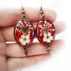 a pair of red earrings with white flowers on them