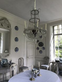 a chandelier hanging from the ceiling in a room with white walls and chairs