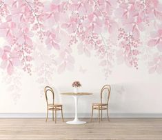 two chairs sitting at a table in front of a wall with pink flowers on it