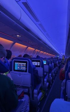 people sitting in seats on an airplane watching something on the screen while others watch them