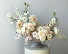 a vase filled with white and pink flowers on top of a cake covered in frosting