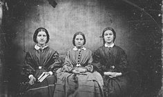 three women sitting next to each other in front of a black and white photo,