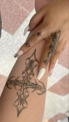 a woman's arm with tattoos on it and a cross tattooed on the side