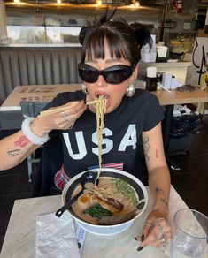 a woman eating ramen with chopsticks at a table in a japanese restaurant