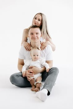 a man, woman and baby are sitting on the floor with their arms around each other