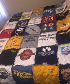 a bed covered in lots of different types of t - shirts on top of it