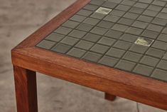 a close up of a wooden table with tile on it's top and bottom