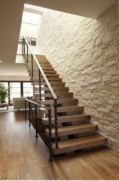 there is a stair case in the middle of this room with wood flooring and stone walls