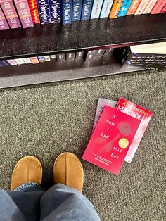 a person standing in front of a book shelf with books on it and a red book