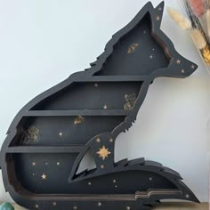 a black and gold painted animal shaped shelf with stars on the bottom, in front of a white wall