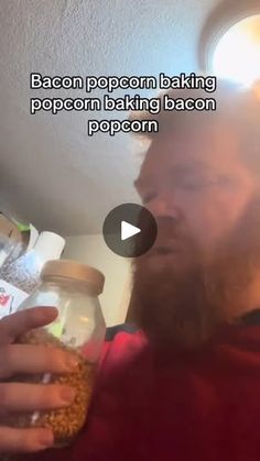 a man with a beard holding a jar of popcorn in his hand and looking at the camera