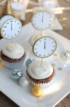 three cupcakes with white frosting and gold trim on top are sitting on a plate