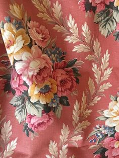 a pink flowered fabric with leaves and flowers on the side, as well as an orange background