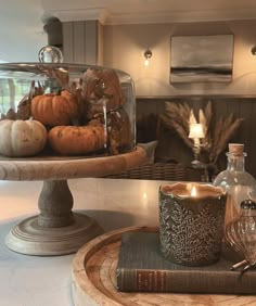 a table topped with a cake covered in lots of pumpkins next to a candle