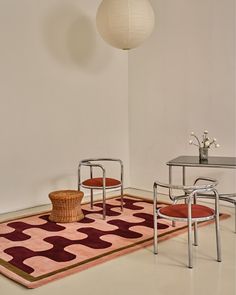 a room with two chairs and a rug on the floor in front of a table