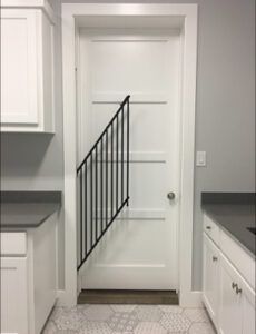 a white door with a black railing in a kitchen