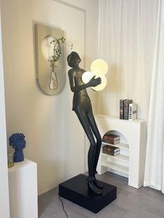 a black statue holding a white light next to a wall mounted shelf with vases on it