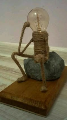 a light bulb sitting on top of a rock with rope wrapped around it's legs