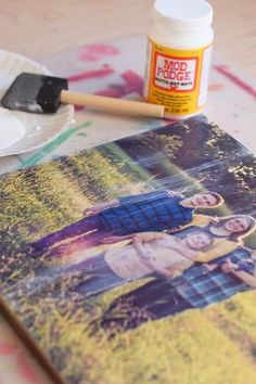 a table topped with paint and a photo on it next to a painting palette, brush and paper plate