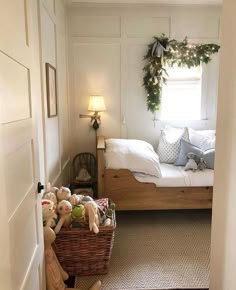 a bed room with a neatly made bed next to a basket filled with stuffed animals