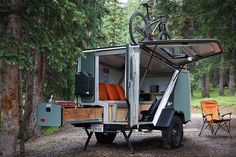 an rv parked in the woods with a bike on top of it's roof