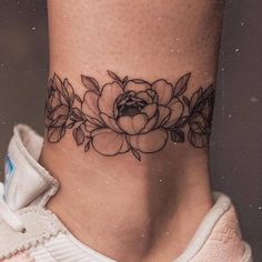 a woman's foot with a flower tattoo on the side of her ankle,