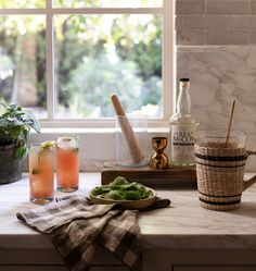 the kitchen counter has two glasses and bottles on it, one is filled with drinks