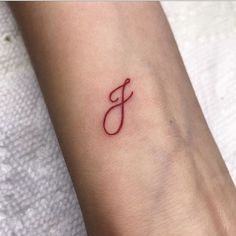 a small tattoo with the letter j on it's wrist, in red ink