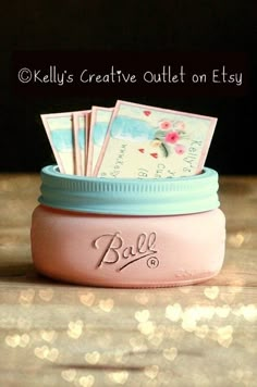 a jar filled with lots of money sitting on top of a wooden table next to a pile of cards