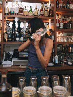 a woman standing behind a bar filled with bottles