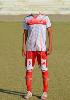 a soccer player is standing on the field wearing red and white uniform with his hands in his pockets