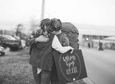 two people hugging each other on the side of the road with cars in the background