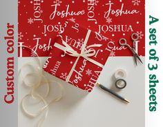 a red gift box sitting on top of a white table next to scissors and ribbon