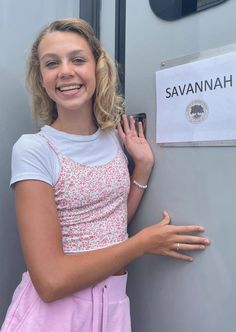 a woman standing next to a door with her hand on the side of the door