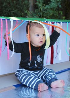 a baby is sitting on the floor with some streamers in front of her head