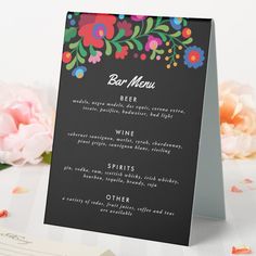 a black menu card with colorful flowers on it