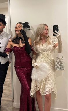 three women in dresses and hats taking a selfie with their cell phones while standing next to each other