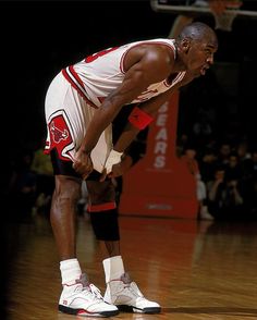 the basketball player is sitting on the court with his hands in his pockets and looking down