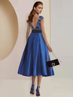 a woman in a blue dress holding a black purse