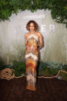 a woman standing in front of a sign wearing a long dress with stripes on it