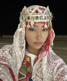 a woman with red hair wearing a white headdress and beads on her head