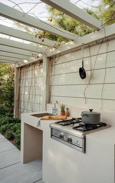 a stove top oven sitting inside of a kitchen under a pergolated roof next to a garden