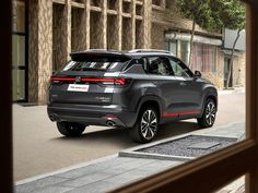 the rear end of a gray suv driving down a street in front of a building